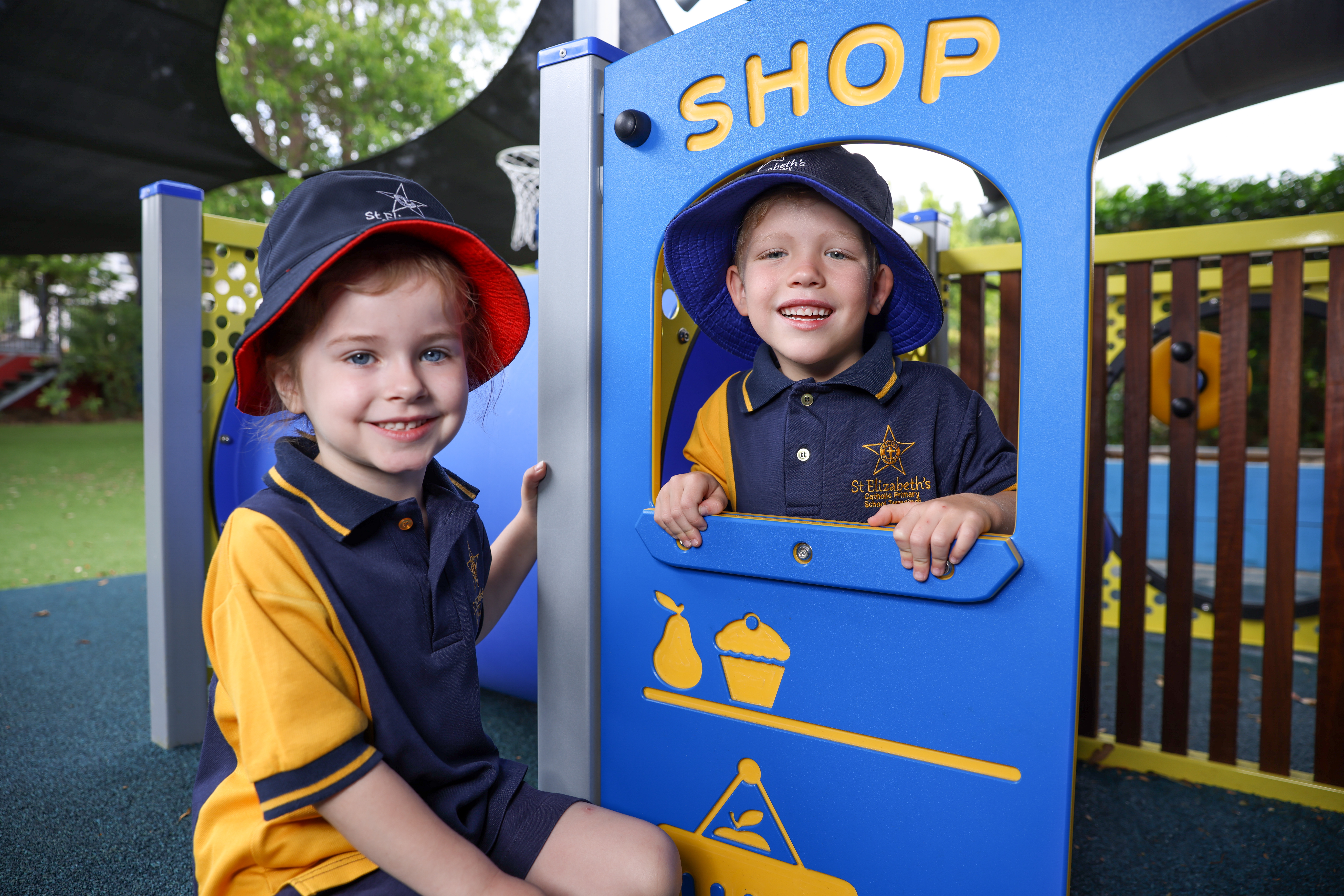 Two young students playing together at the school shop playground structure, highlighting imaginative play friendship and enjoyment within a supportive early years learning environment