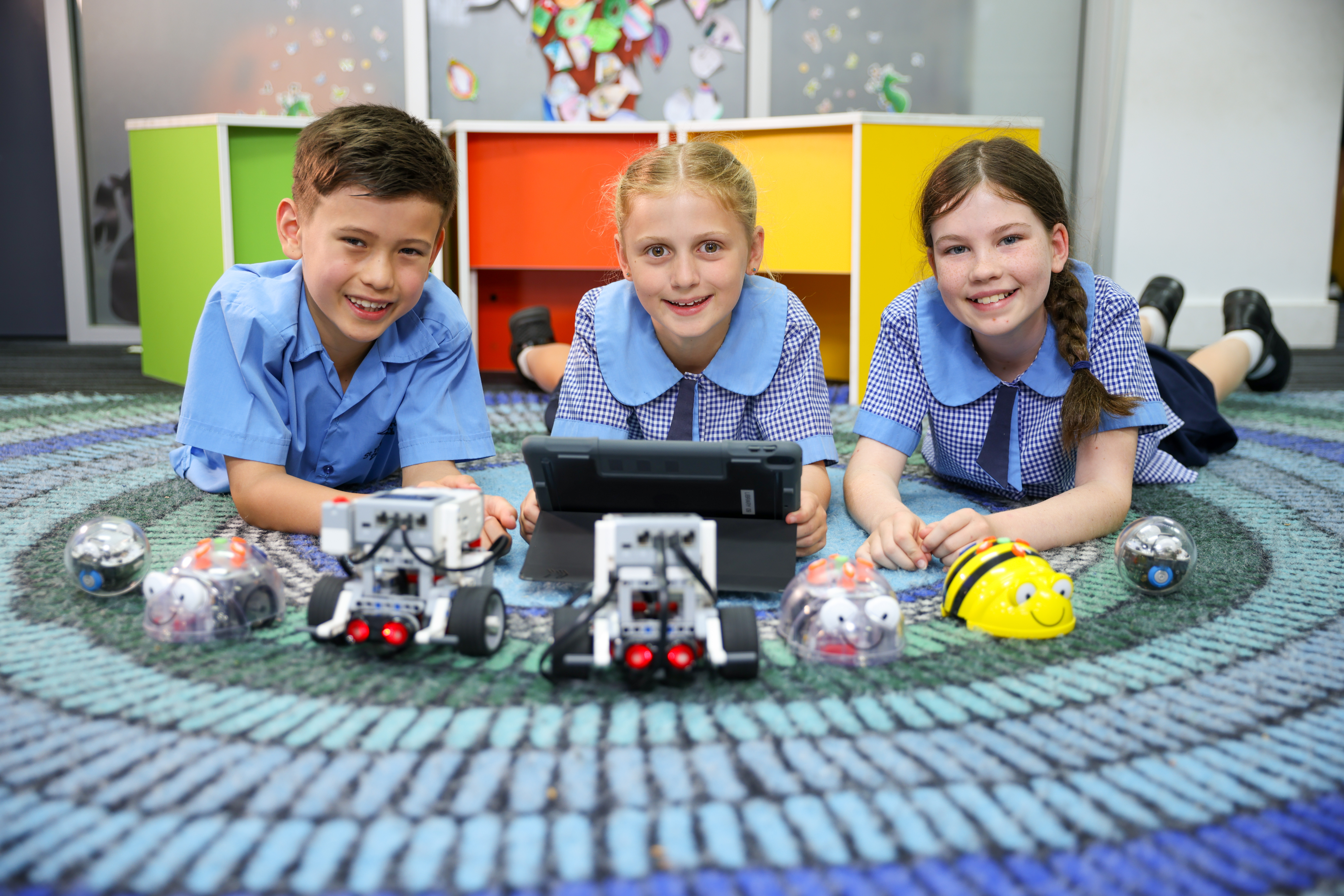 Students working together with robotics equipment and a tablet on the classroom floor, highlighting collaborative STEM learning, problem solving and digital inquiry