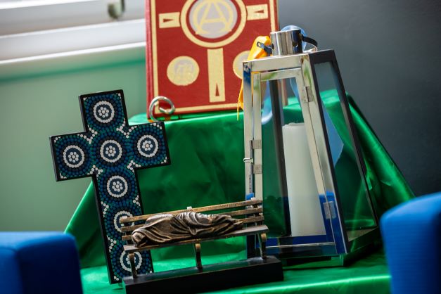 Prayer and reflection table displaying a cross lantern scripture and faith symbols supporting Catholic identity prayer and spiritual reflection within the school community