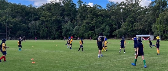 Students participating in a team sport session on the school oval, highlighting physical activity teamwork and skill development through outdoor sport
